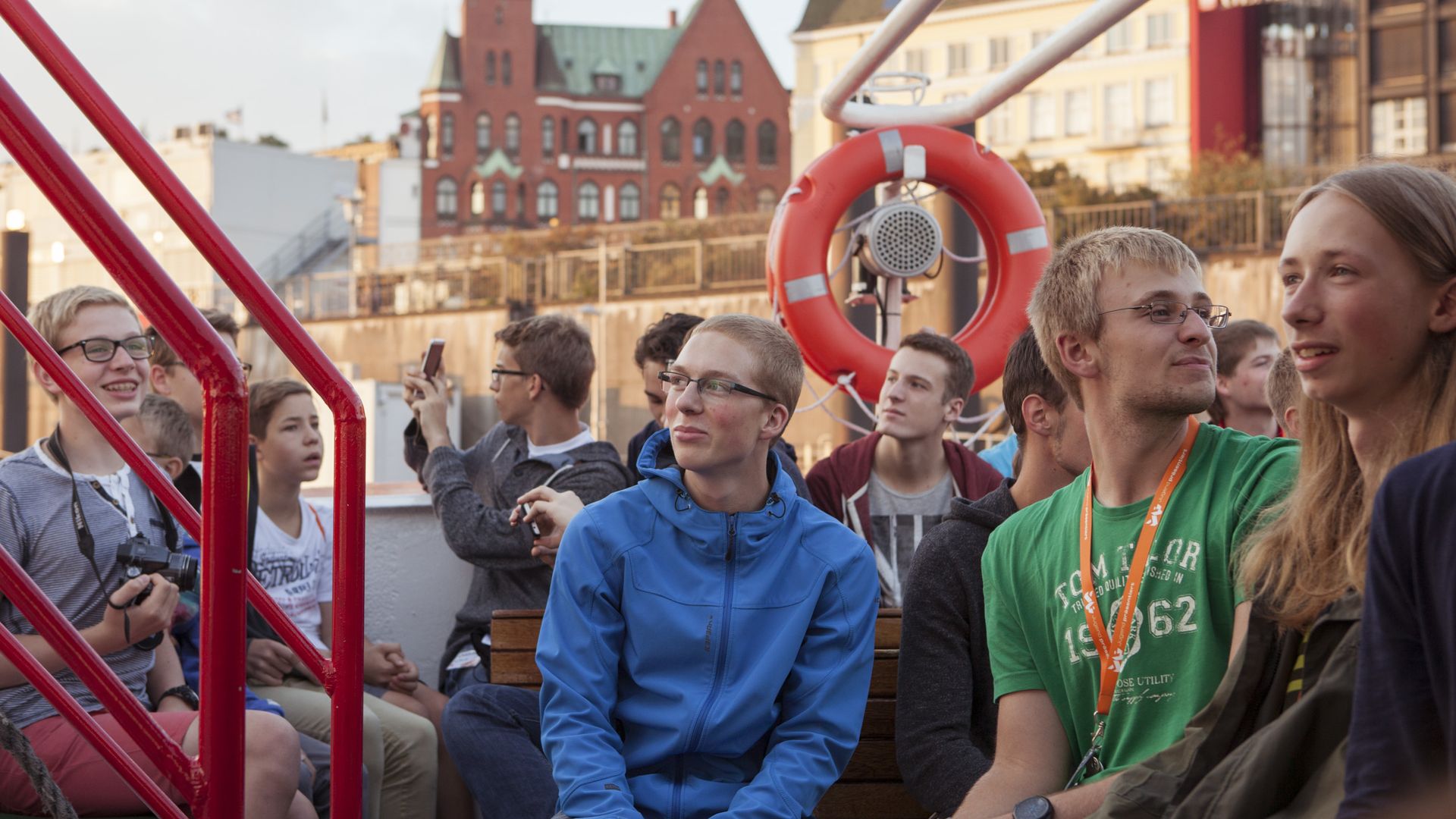 Junge Menschen sitzen in einem Schiff, das durch den Hamburger Hafen fährt.