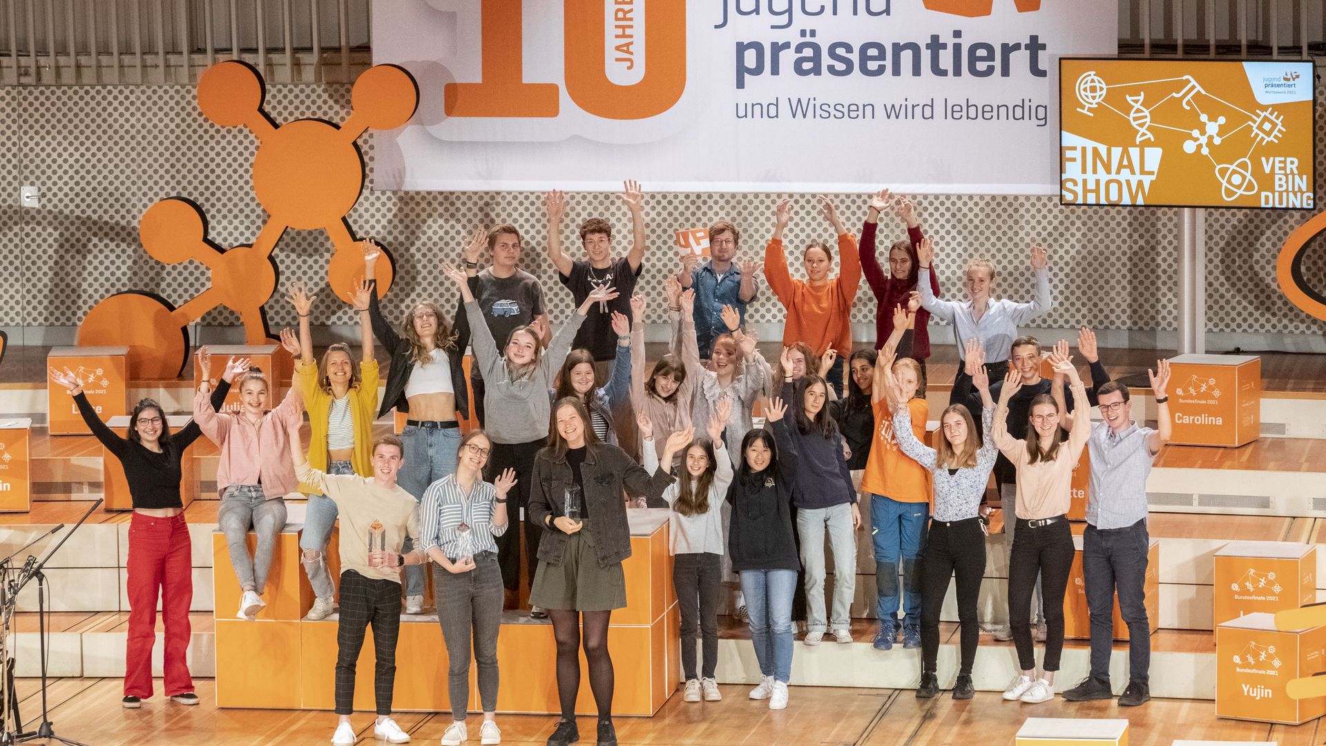 Jubelnde Menschen stehen auf einer großen Bühne, im Hintergrund steht "10 Jahre Jugend präsentiert"