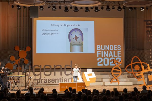 Schüler präsentiert auf der Bühne zum Thema Fingerabdruck.