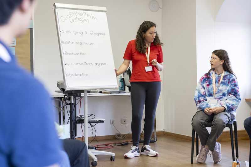 Trainer*in beantwortet einem Schüler eine Frage während der Präsentationsakademie.