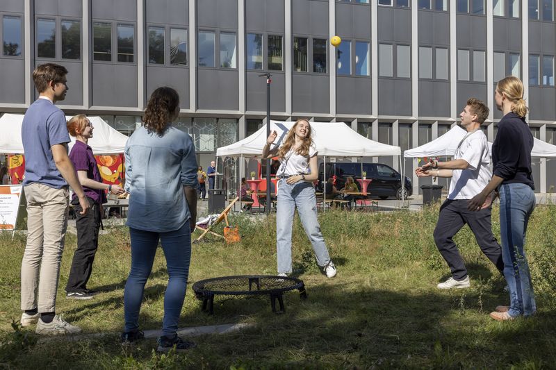 Teilnehmer spielen im Kreis Spikeball.