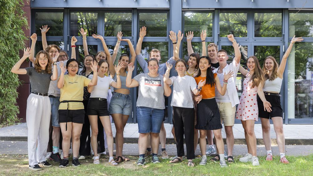 Eine Gruppe junger Menschen jubelt in die Kamera.
