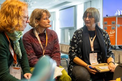 Bild dreier Frauen mit Arbeitsblättern vor sich. Sie sitzen.