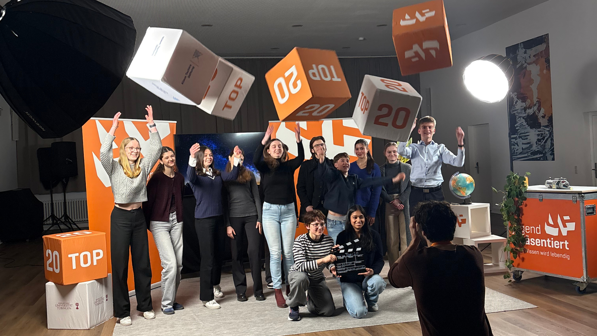 Teilnehmer*innen beim Top-20-Dreh springen in die Luft und machen ein Gruppenfoto.