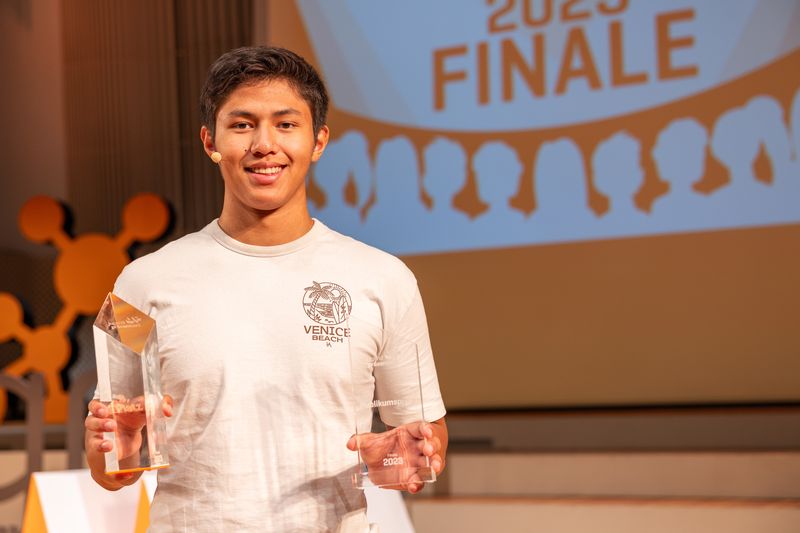 Der Schüler Hatim Abdel Ghaffar hält in jeder Hand einen Pokal, einmal die Auszeichnung für den dritten Platz und einmal den Publikumspreis.