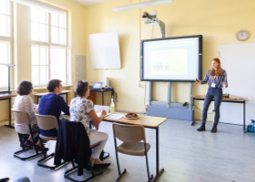 Schülerin präsentiert vor einer Jury im Klassenzimmer.