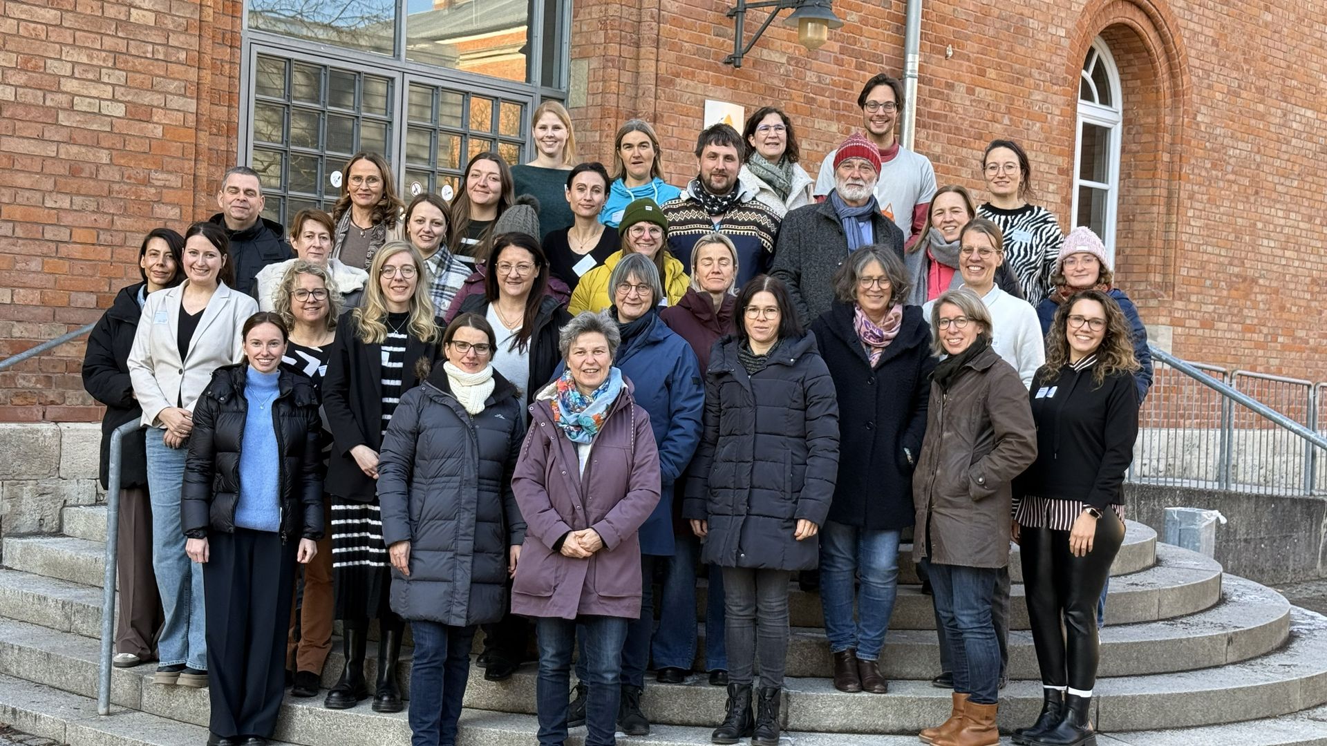 Eine Gruppe Lehrkräfte steht auf einer Treppe und lässt sich für ein Gruppenfoto fotografieren.